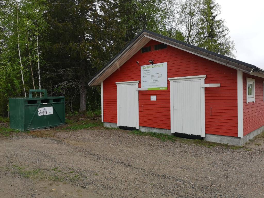 Punainen kierrätyspiste kuvattuna ulkoa.